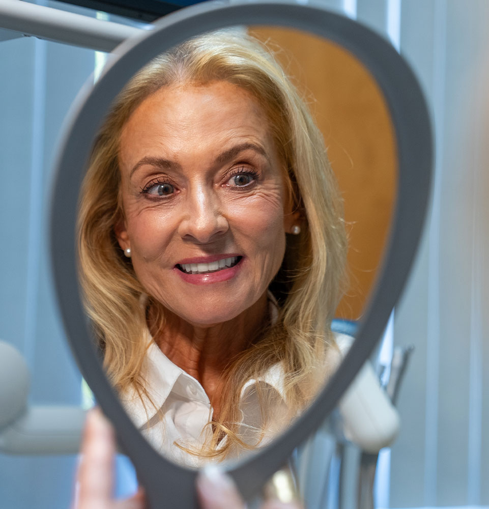 Patient looking into mirror smiling